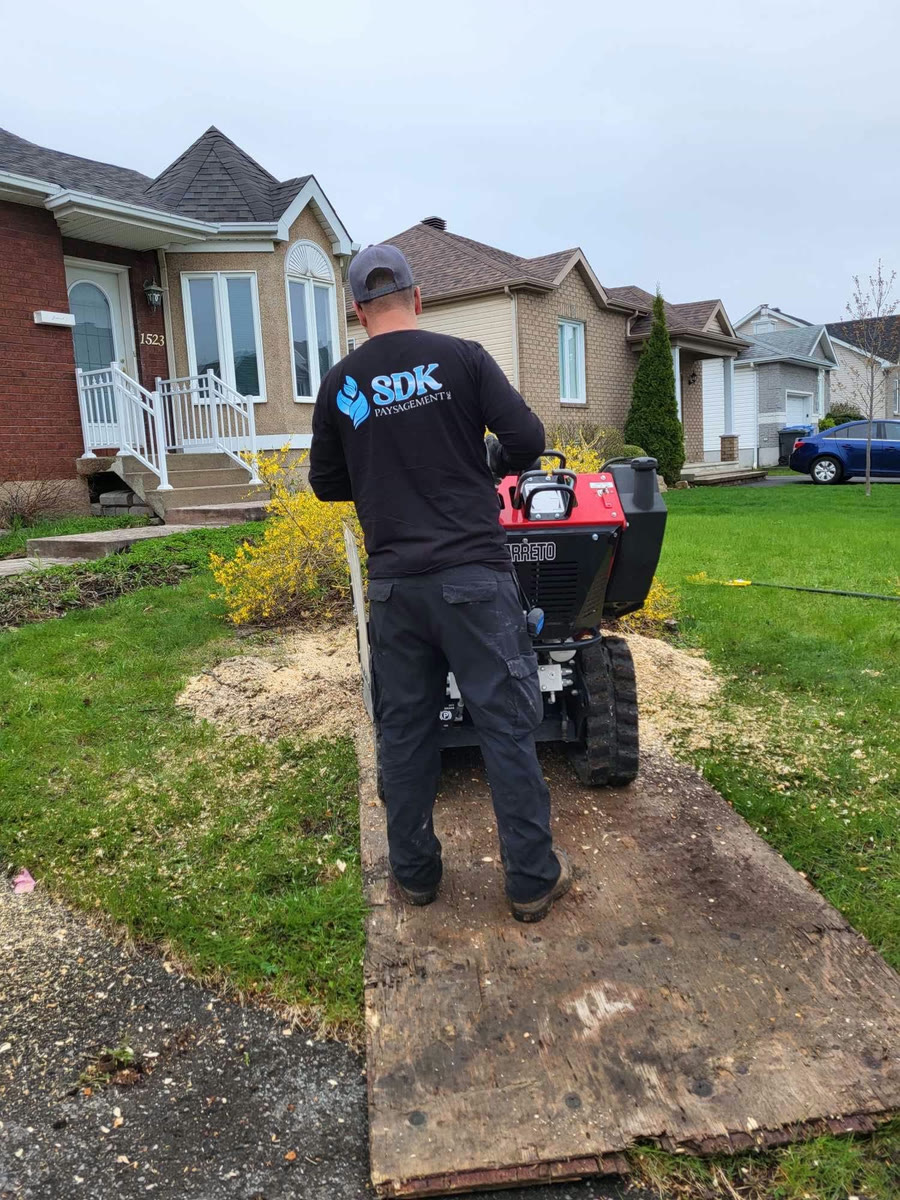 Technicien de SDK Paysagement Inc. tondant une pelouse résidentielle